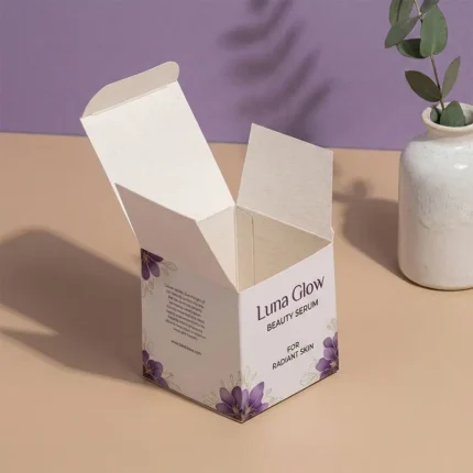 An open "Luna Glow Beauty Serum" box with purple floral accents, displayed next to a white vase and green leaves.